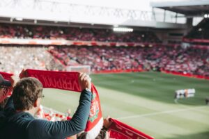 Man holding a Liverpool football scarf at a premier league football match
