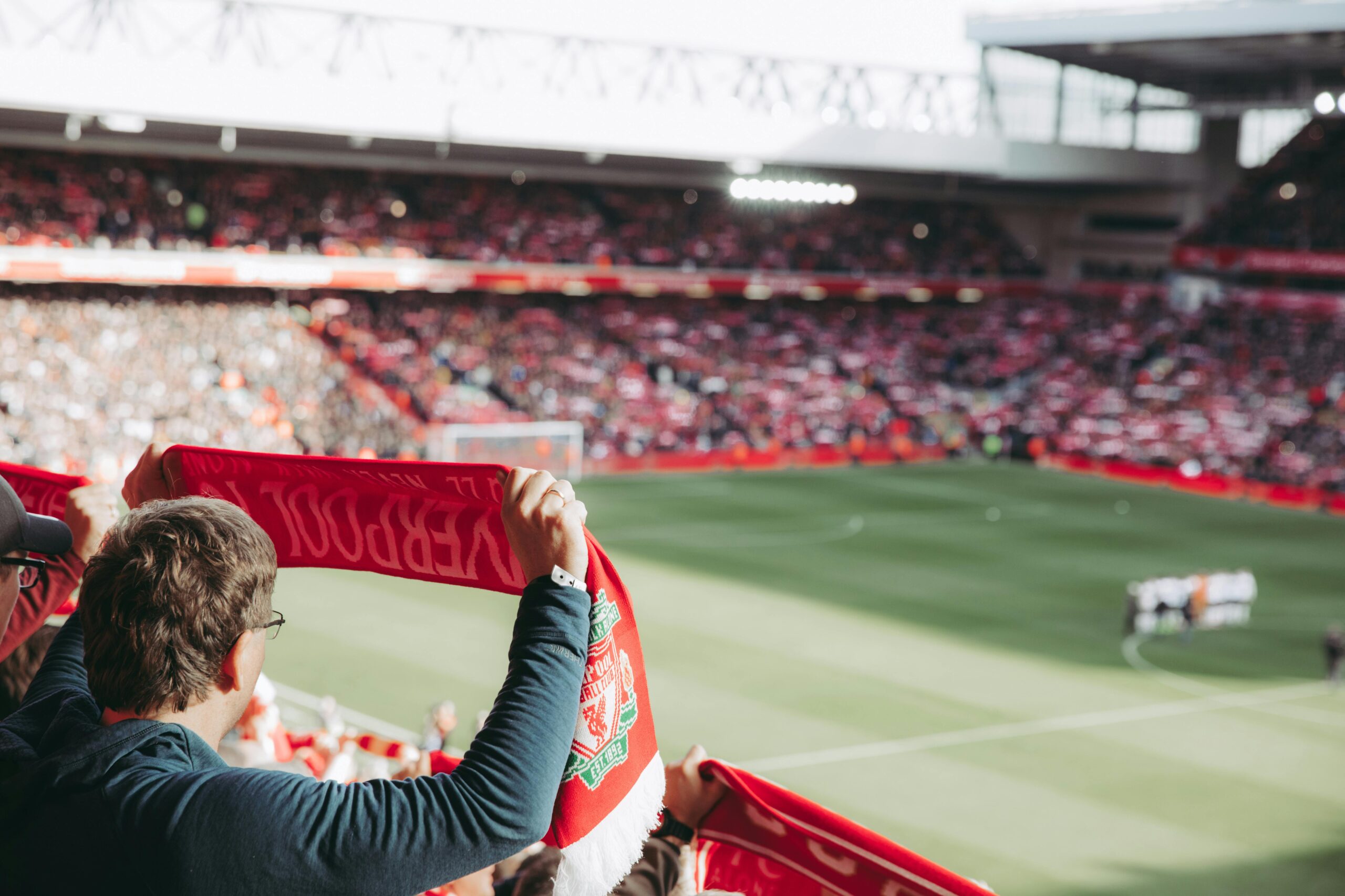 Man holding a Liverpool football scarf at a premier league football match
